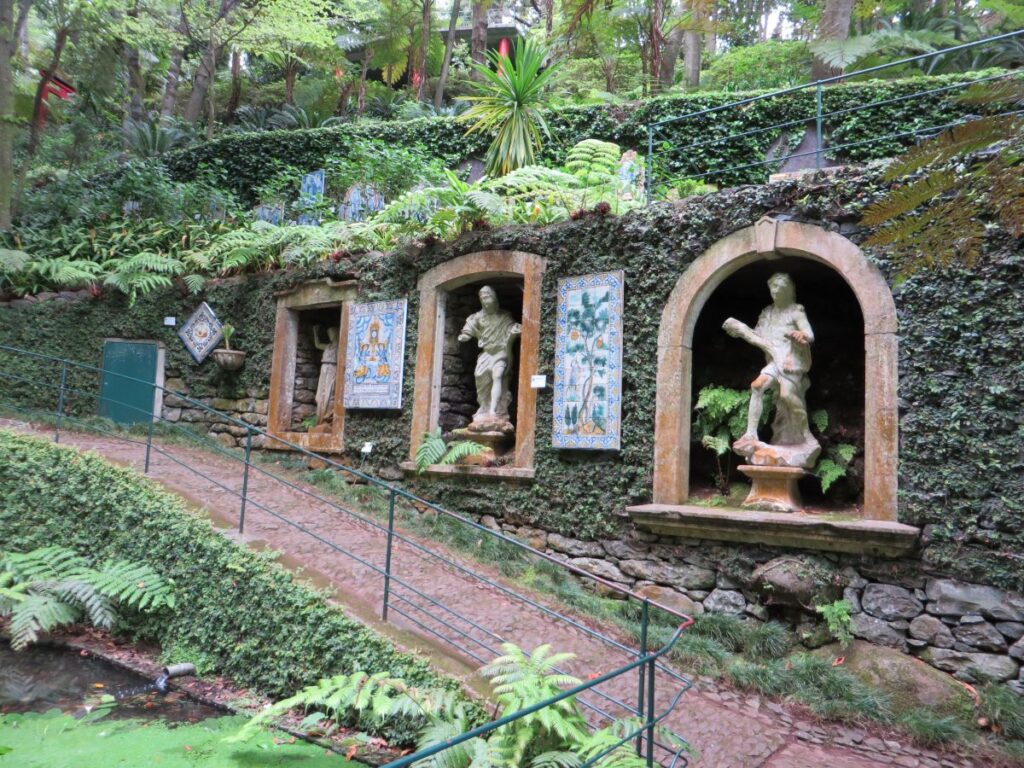 Pannelli di azulejos portoghesi e sculture nel muro di pietra ricoperto di edera del Monte Palace Tropical Garden a Madeira